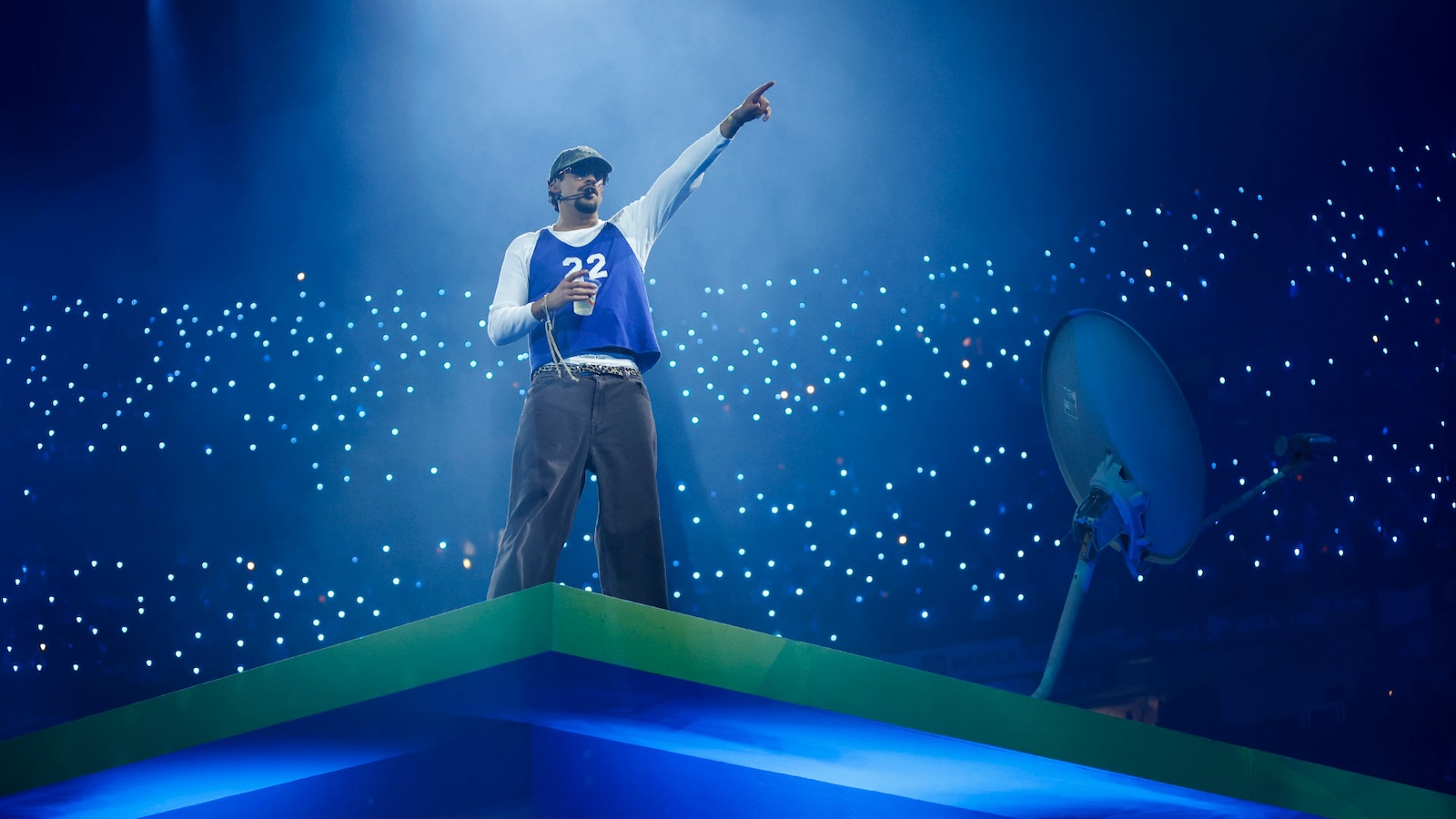 Performer Bad Bunny raises his hand in a concert venue.