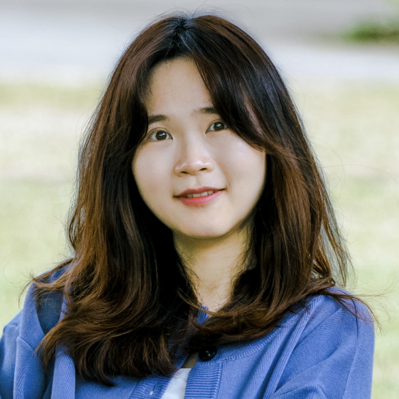 Mei Nan smiling outdoors in a blue cardigan.