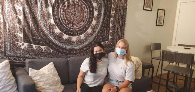 two students sitting in front of a tapestry